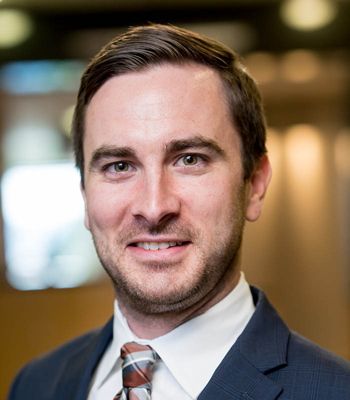 Meet Our Team - Professional and Welcoming Group at a Conference Table Faces the Camera, Team Leader Sitting on the Table with Arms Folded